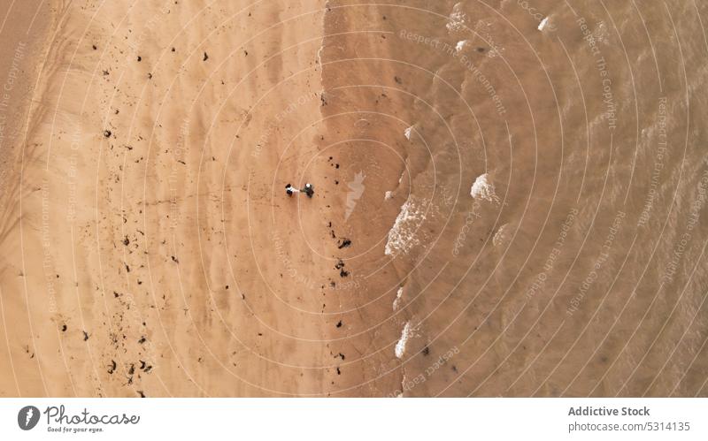 Drohnenansicht von unerkennbaren Personen am Sandstrand in der Nähe des Ozeans Meer Strand Küste Ufer schäumen wellig winken Republik Irland Natur Küstenlinie