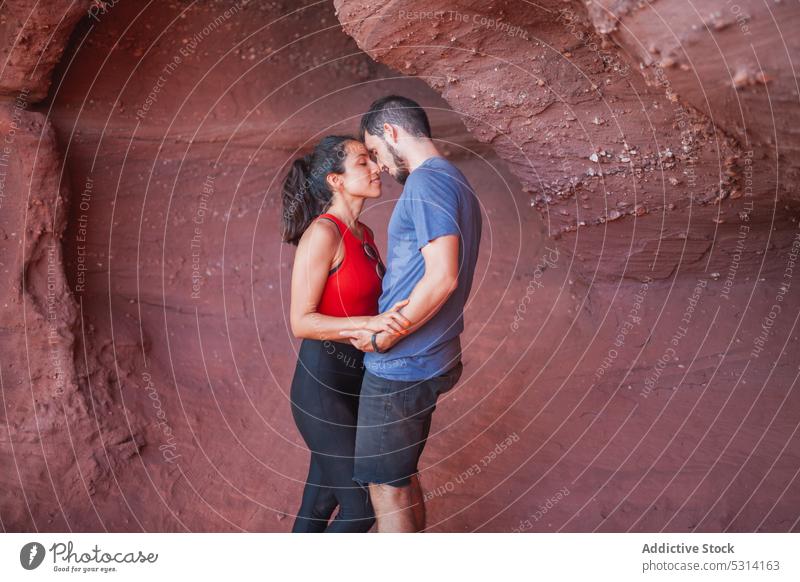 Verliebtes Paar umarmt sich in einer Schlucht Umarmen Höhle sanft Berührungsnase Liebe reisen Urlaub Umarmung Lächeln Glück rote Schlucht ethnisch hispanisch