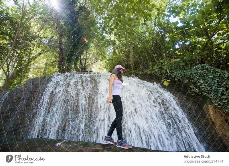 Sorglose Frau balanciert in der Nähe eines Wasserfalls im Wald Wanderung Wanderer Felsbrocken Kofferraum Gleichgewicht reisen Natur Ausflug Zaragoza Spanien
