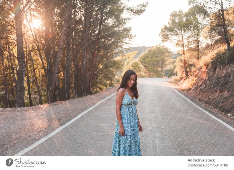 Unbekümmerte Frau steht an einer Straße im Wald Reisender Asphalt Sommer Sonnenuntergang Großstadt Spaziergang Baum Urlaub Zaragoza bewundern Spanien Kleid