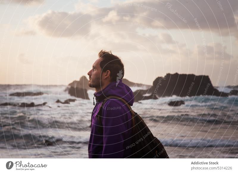 Mann vor dem Meer stehend MEER Ufer Sonnenuntergang Strand wolkig Himmel Küste Reisender Abend Urlaub winken Wasser männlich sich[Akk] entspannen Abenddämmerung