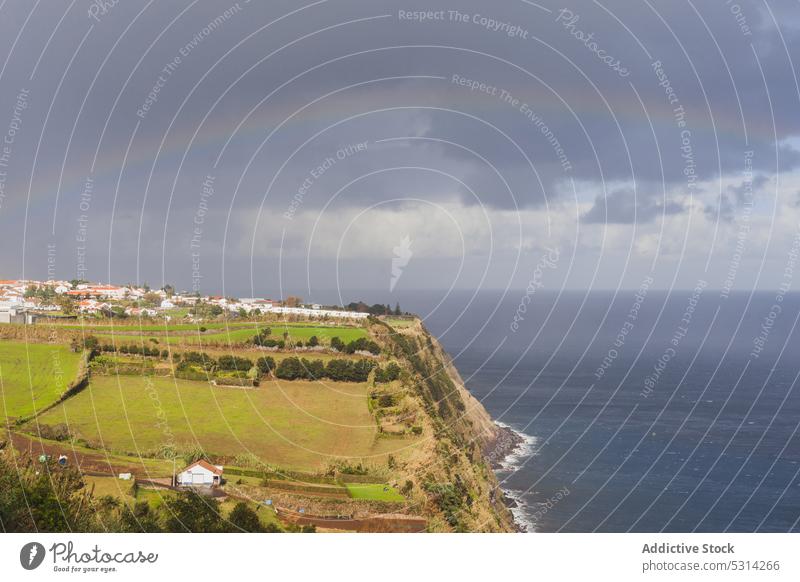Malerische Kulisse des endlosen Ozeans in der Nähe des Dorfes unter dem Regenbogen Meer Klippe MEER wolkig winken malerisch Landschaft Wohnsiedlung Azoren