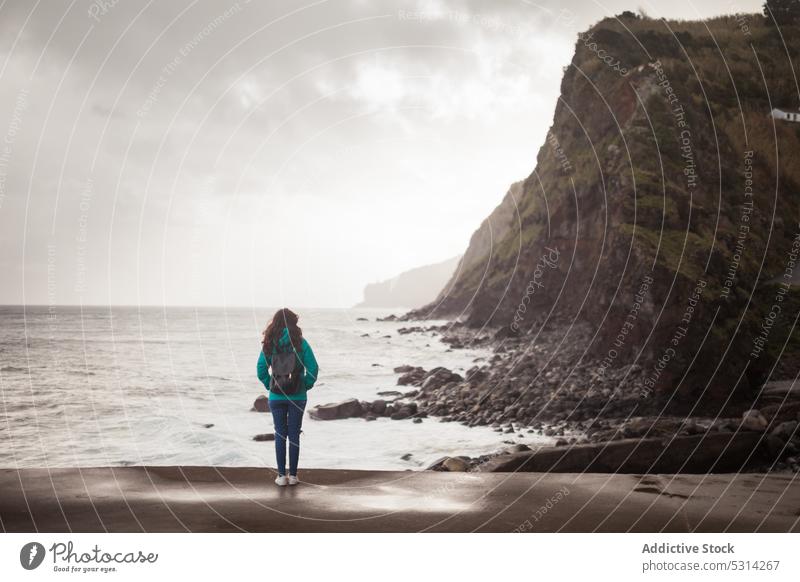 Frau in Oberbekleidung bewundert das Meer an einem düsteren Tag Reisender Tourist MEER Klippe trist wolkig bedeckt nass bewundern Insel Azoren Portugal Europa