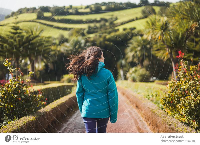 Frau geht entlang einer tropischen Straße an einem sonnigen Tag Reisender Tourist Spaziergang Weg Hügel exotisch Baum Pflanze bewundern Azoren Portugal Europa