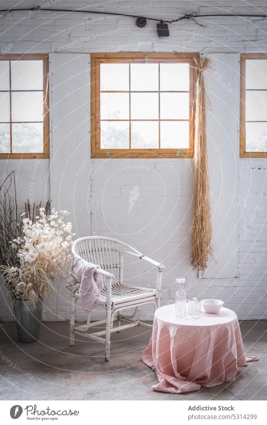 Stuhl am Tisch mit Serviette vor dem Fenster Dekor Blume Möbel Appartement Innenbereich Raum Backsteinwand Design Vase heimwärts hölzern weiß