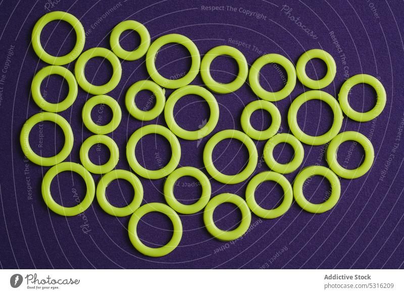 Bunte Kunststoffringe auf violetter Oberfläche Ringe kreisen farbenfroh modern kreativ hell schön sehr wenige Phantasie Textur Hintergrund Form Design abstrakt