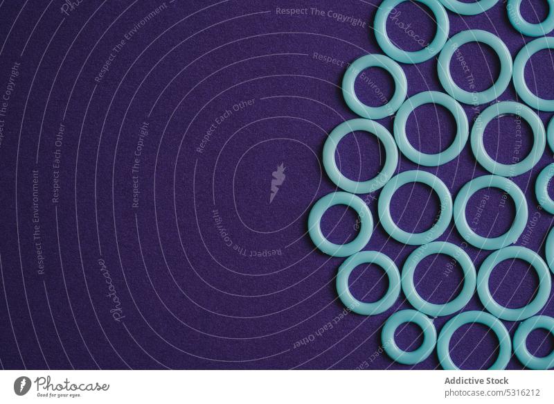 Bunte Kunststoffringe auf violetter Oberfläche Ringe kreisen farbenfroh modern kreativ hell schön sehr wenige Phantasie Textur Hintergrund Form Design abstrakt