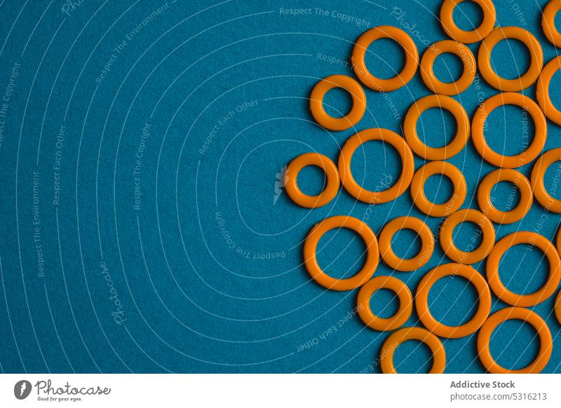 Bunte Kunststoffringe auf blauer Oberfläche Ringe kreisen farbenfroh modern kreativ hell schön sehr wenige Phantasie Textur Hintergrund Form Design abstrakt