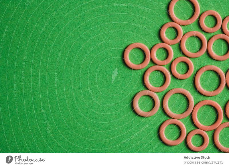 Bunte Kunststoffringe auf grüner Oberfläche Ringe kreisen farbenfroh modern kreativ hell schön sehr wenige Phantasie Textur Hintergrund Form Design abstrakt