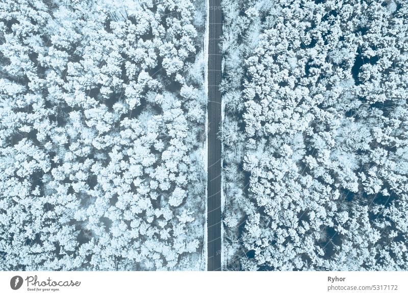 Luftaufnahme von Autobahn Straße durch Schnee Waldlandschaft im Winter. Top view flache Ansicht der Autobahn Autobahn aus hoher Haltung. Reise und Reisekonzept