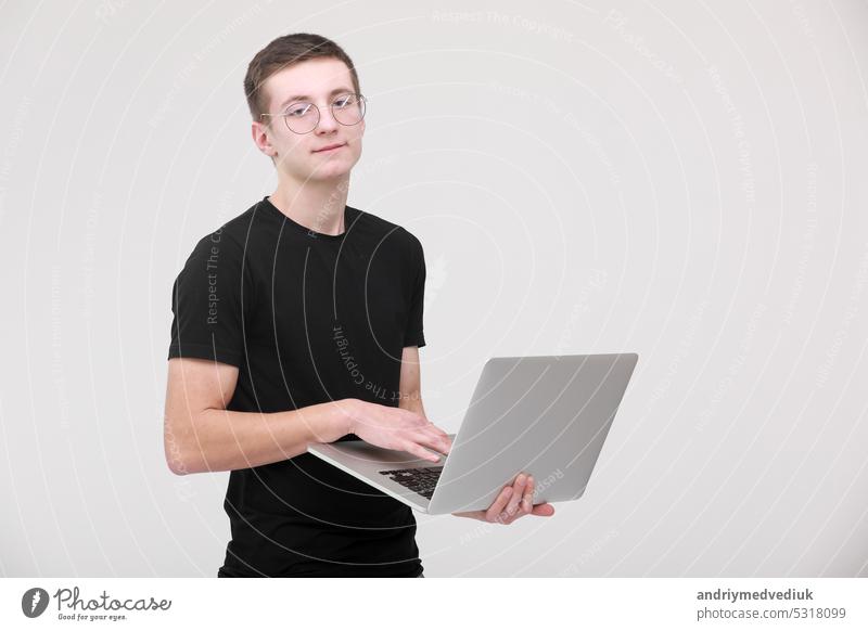 Online-Fernunterricht. Porträt eines jungen Mannes in einem schwarzen T-Shirt mit Brille und einem Laptop auf weißem Hintergrund. copy space Business Computer
