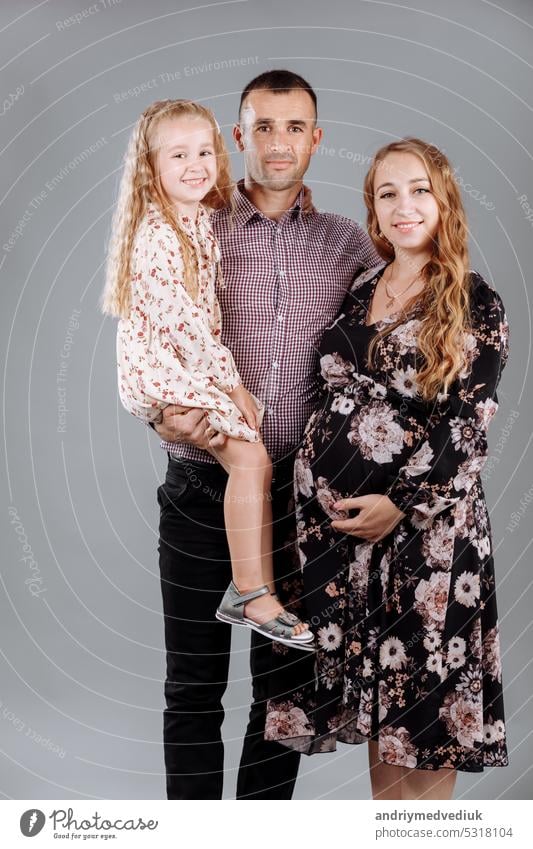 Porträt einer glücklichen Familie Vater, schwangere Mutter, kleine Tochter, die Spaß zusammen isoliert über grauen Hintergrund wenig vereinzelt Glück Mädchen