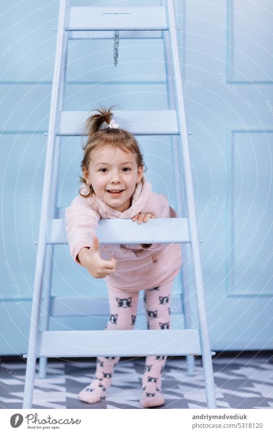 Lächelnde schöne kleine Mädchen in Einhorn rosa Kostüm ist lächelnd und Spaß auf einer blauen Wand Hintergrund. glückliche Kindheit. wenig Hut Gesicht niedlich