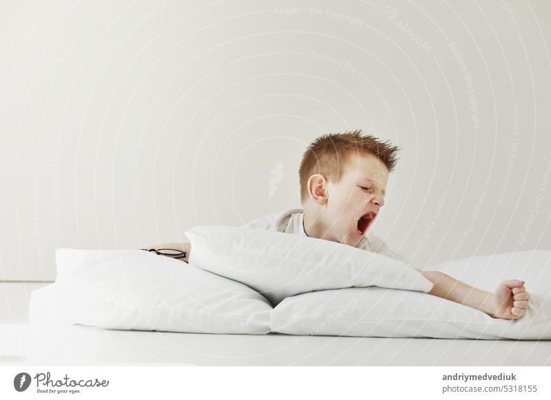 Kind Junge wacht auf und Stretching auf seinem bequemen Bett am Morgen, Gesundheitsversorgung und guten Morgen Welt Konzept. Dehnt sich und gähnt. Lifestyle