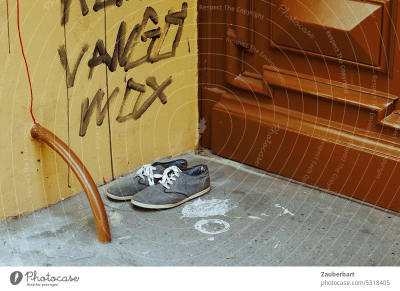 Ein Paar Schuhe steht im Hauseingang vor Graffiti und Tür aus Gründerzeit paar Sneaker bequem Eingang abgestellt warten stehen ausziehen aufbrechen Füße gehen