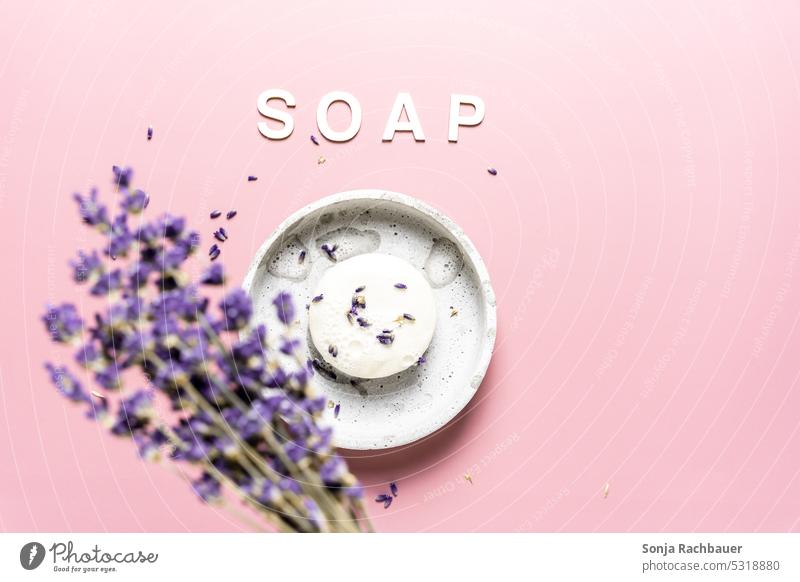 Ein rundes Seifenstück mit Lavendel auf einem rosa Hintergrund. Draufsicht. Schaum Sauberkeit hygiene Körperpflege selbstgemacht Kosmetik Bad Wellness Spa