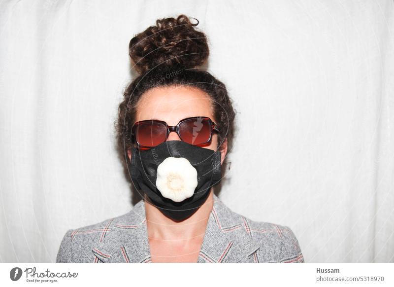 Fotokonzept über eine Person, die eine medizinische Maske mit einem Knoblauchkopf darin trägt Pandemie Behandlung Medikament Nahaufnahme Pflege Schutz