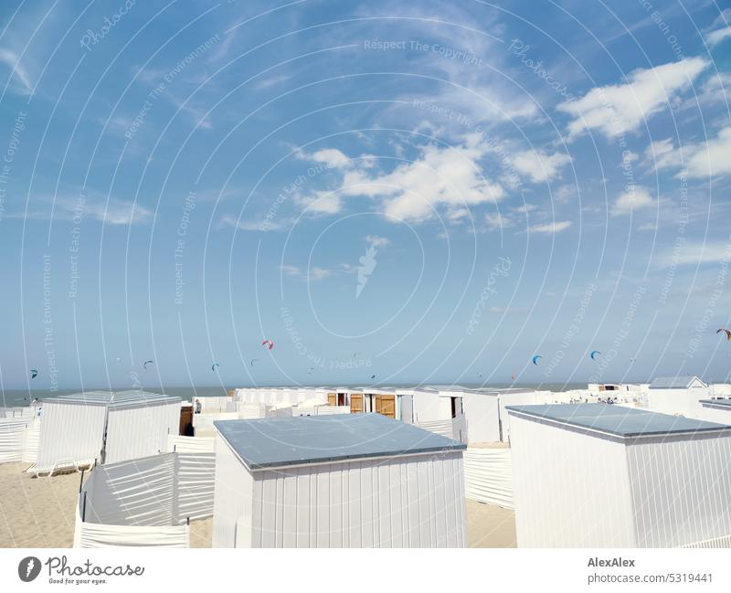 Weiße Strandhäuschen am Strand der Nordsee mit Kites im Hintergrund am Himmel Meer Küste weiß blauer Himmel Surfen Sand Natur Blauer Himmel Landschaft