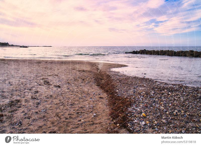 Steinstrand auf dem Darss bei Sonnenuntergang. Ostsee mit leichten Wellen und Pastellfarben am Himmel. Landschaftsfoto von der Küste Strand Sand Urlaub