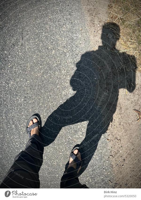 Eigener Schatten bei Blick auf die Straße Schattenwurf Sonnenlicht Silhouette Kontrast Licht & Schatten Außenaufnahme Farbfoto Füße auf dem Boden Sandalen