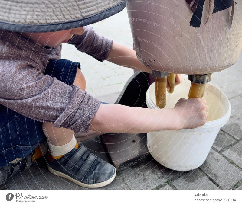 Kind übt melken an einer Kuhattrappe Euter Attrappe Milch üben ausprobieren Eimer Zitzen Bauernhof Konzentration Kindheit Landwirtschaft Tier vegan ungesund