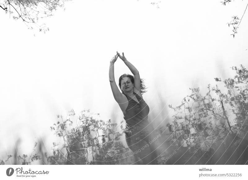 Frau tanzt im Einklang mit der Natur hinter hohen Gräsern tanzen Natur erleben feminin reife Frau Mensch Harmonie genießen Mensch und Natur Wahrnehmung Sinne