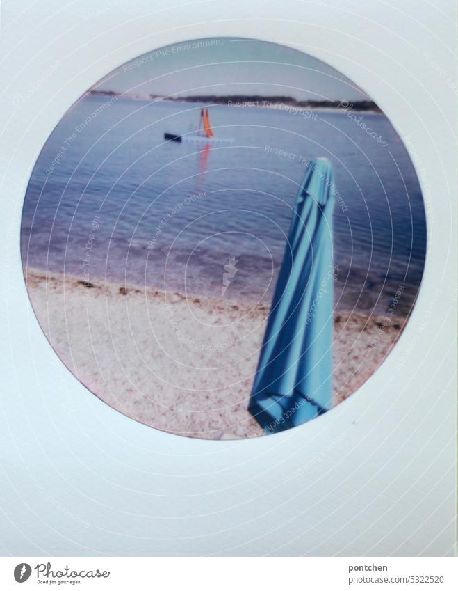 polaroid zeigt einen hellblauen  sonnenschirm am steinstrand und eine rote rutsche im meer kroatien urlaub reisen wasser Ferien & Urlaub & Reisen Strand Küste