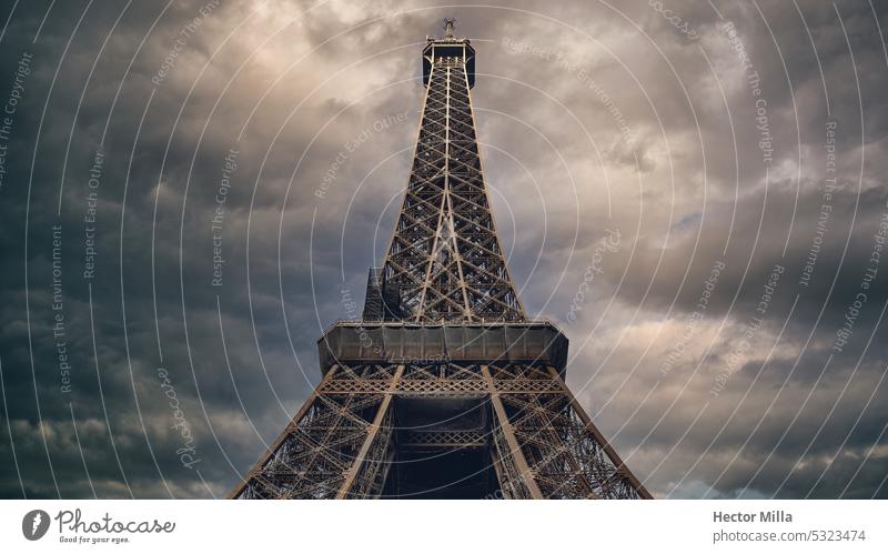Der Eiffelturm in seiner ganzen Schönheit vor einem grauen und stürmischen Himmel mit Glanz auf dem Metall, historische Konstruktion Paris urban Ansicht