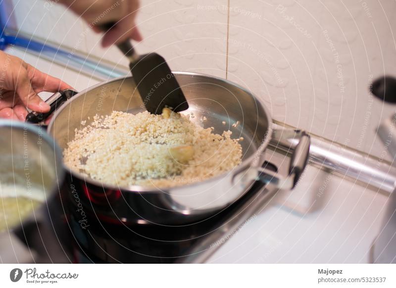 Menschliche Hand mit Kochutensil, die Reis mit Knoblauch umrührt Rezept weiß Speise Aroma Kaukasier Nahaufnahme Essen zubereiten Textfreiraum Küche lecker Diät
