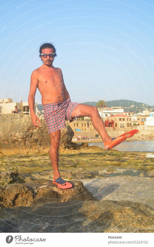 Foto eines Mannes, der eine Schwimmbrille und Schwimmflossen an den Füßen trägt und sich in lustiger Pose auf das Schwimmen vorbereitet Schwimmhilfe