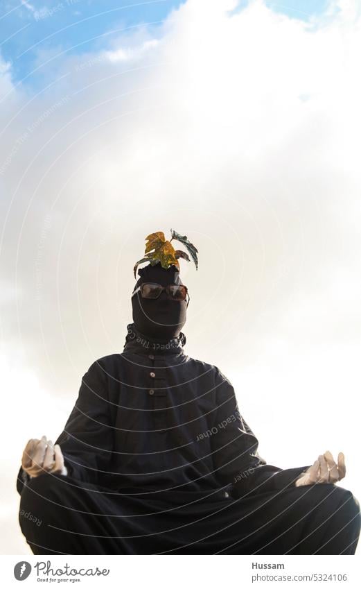 Fotokonzept über eine Person in Meditationshaltung, bedeckt mit schwarzer Kleidung und Pflanze auf dem Kopf und mit weißen Handschuhen Spiritualität