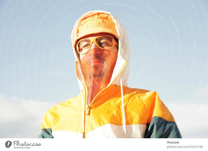 Foto-Konzept über eine Person, die ein Sport-Outfit und orangefarbenen Hut mit transparenter Maske und funky Brille ohne Glas trägt Lifestyle flippig