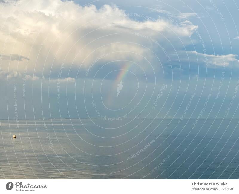Ein Regenbogen und hübsche Wolken über der ruhigen Nordsee, im Hintergrund Windkraftanlagen auf dem Festland Ruhe sanftes Licht Reflexion & Spiegelung Himmel