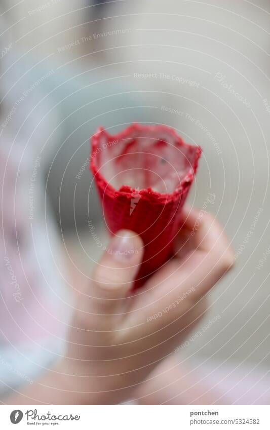 ein kind hält eine rote, angeknabberte, eiswaffel mit resten von eis in der hand. eis essen besonders kindheit genuss freude lecker Speiseeis süß Essen