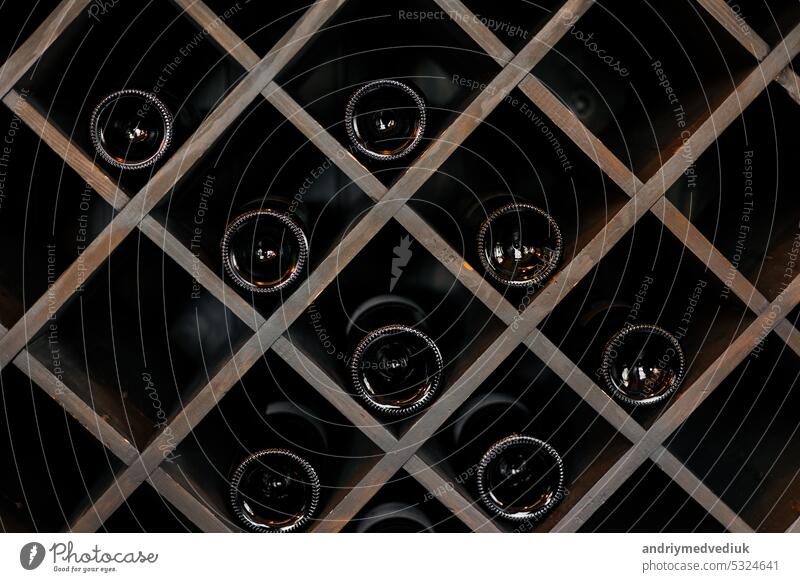 Elite dunklen Glas Weinflaschen auf Holzregalen im Keller, Markt, Restaurant oder zu Hause gestapelt. Sammlung von Flaschen Wein im Regal Alkohol hölzern