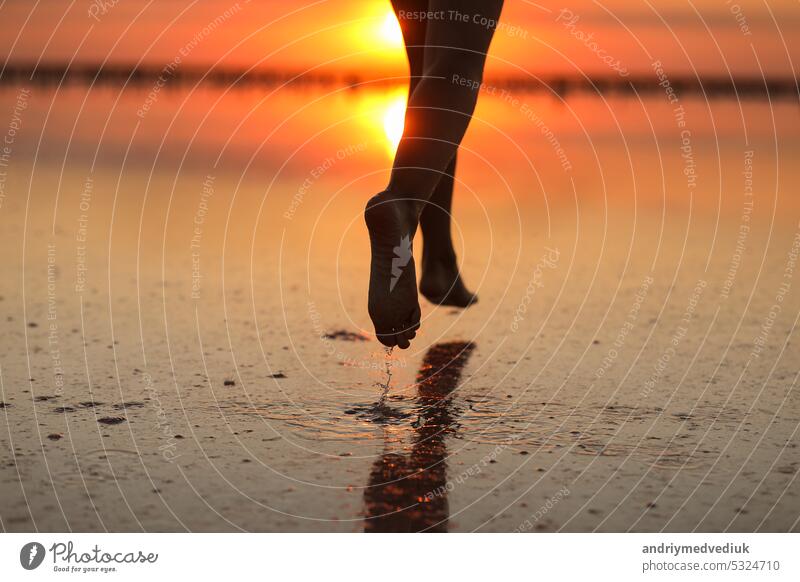 Aktive Sommerreise Urlaub. Cropped Foto der Beine Silhouette von Energie kleines Kind Mädchen, Junge mit Spaß läuft und spielt am Strand bei Sonnenuntergang. Jugend, Lebensstil und Glück Konzept. Tag der Kinder