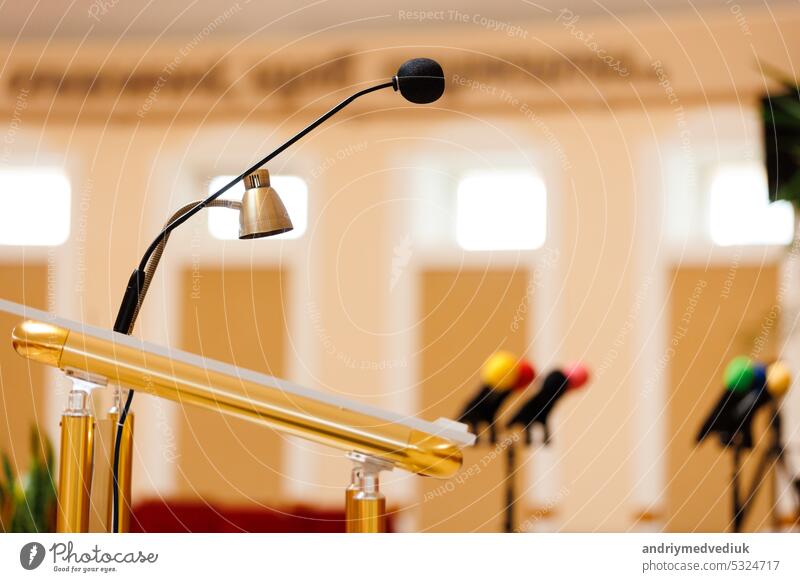 Selektiver Fokus eines Mikrofons mit anderen bunten Mikrofonen auf dem Podium im Hintergrund verschwommen. Konzept der Kommunikation, Medien, Pressekonferenz, Veranstaltung, Leistung, Politik, Unternehmen.