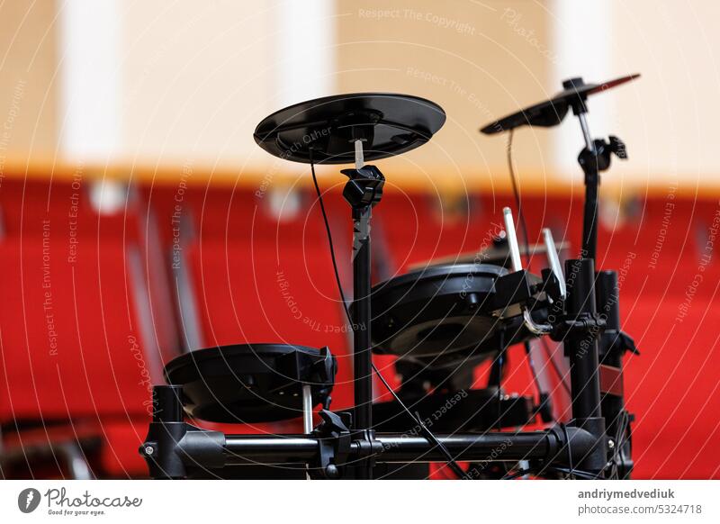 Elektronisches Schlagzeug auf dem Podium, viele rote Stühle im Hintergrund. Konzept für Konzert, Veranstaltung, Kommunikation, Seminar, Medien, Abschlussfeier, Performance