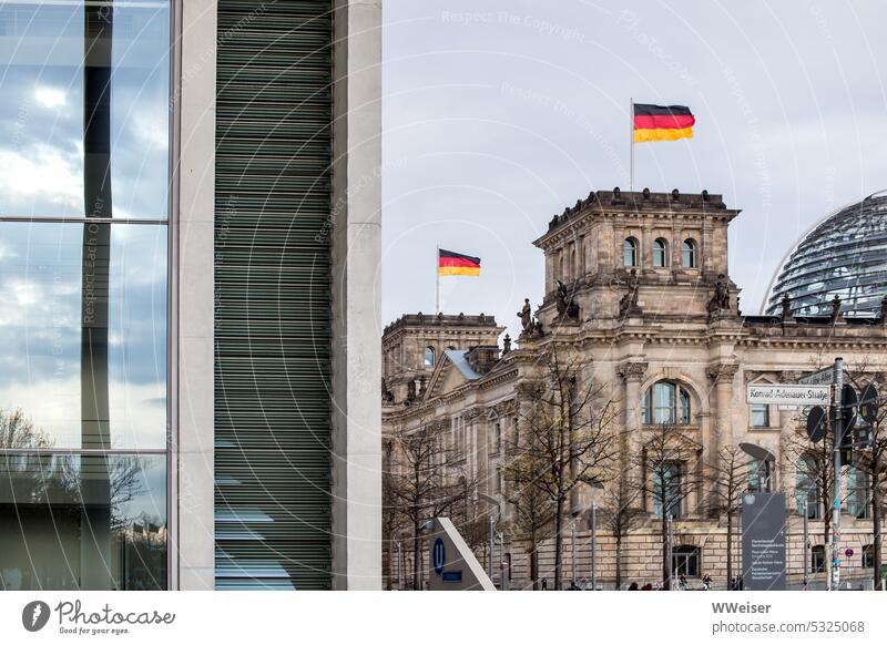 Der Reichstag bzw. der Deutsche Bundestag in Berlin mit wehenden Fahnen und ein weiteres Regierungsgebäude Parlament Deutschland Republik Hauptstadt