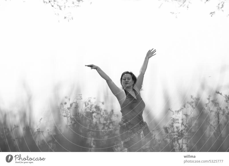 Frau tanzt hinter Gräsern in den Mai tanzen Freude Natur erleben genießen Mensch und Natur reife Frau Arme Harmonie feminin sw