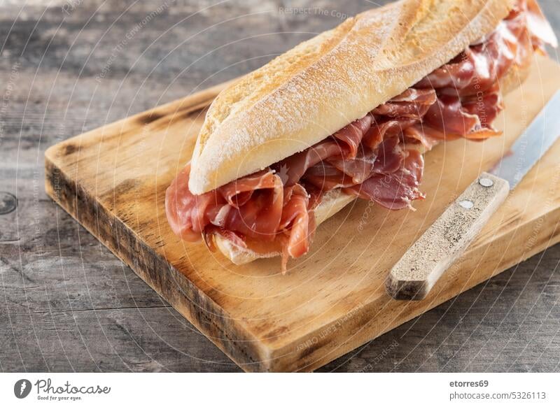 Sandwich mit spanischem Serrano-Schinken auf Holztisch Baguette bocadillo Brot Feinkostladen lecker Lebensmittel Gastronomie Feinschmecker selbstgemacht