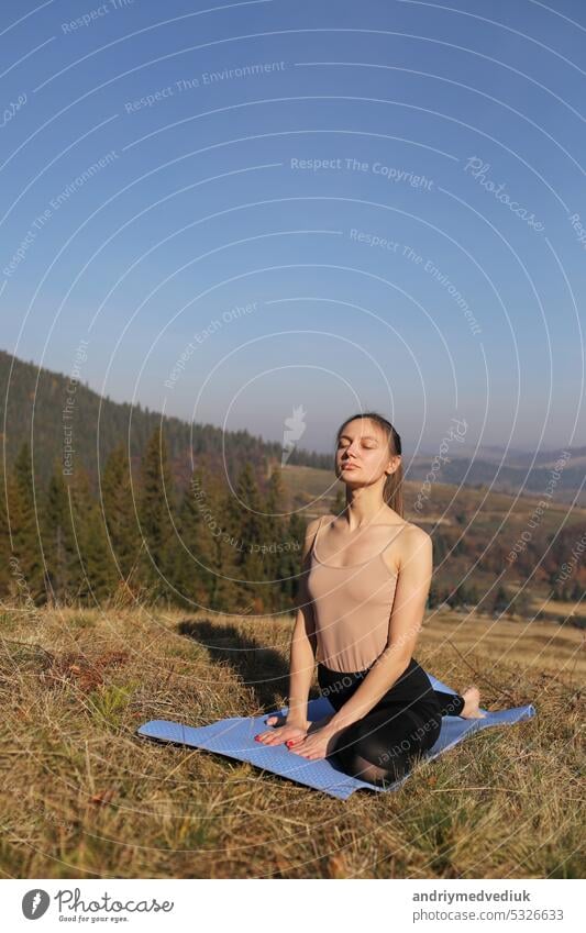 Junges Mädchen macht Yoga Fitness-Übung im Freien in schönen Bergen Landschaft. Mädchen tun Morgengymnastik auf einer Wiese in den Bergen. Meditation und Entspannung. Gesunder Lebensstil.