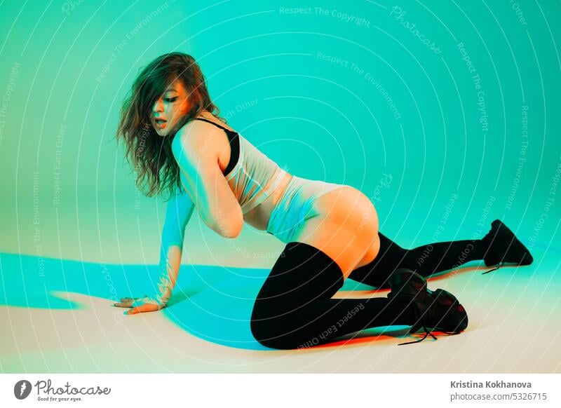 Frau führt flexible Bewegungen, twerking Körper auf dem Boden. Heißer Tanz in Neon Tanzen neonfarbig Leistung jung schön Schönheit Mode Mädchen Licht Musik