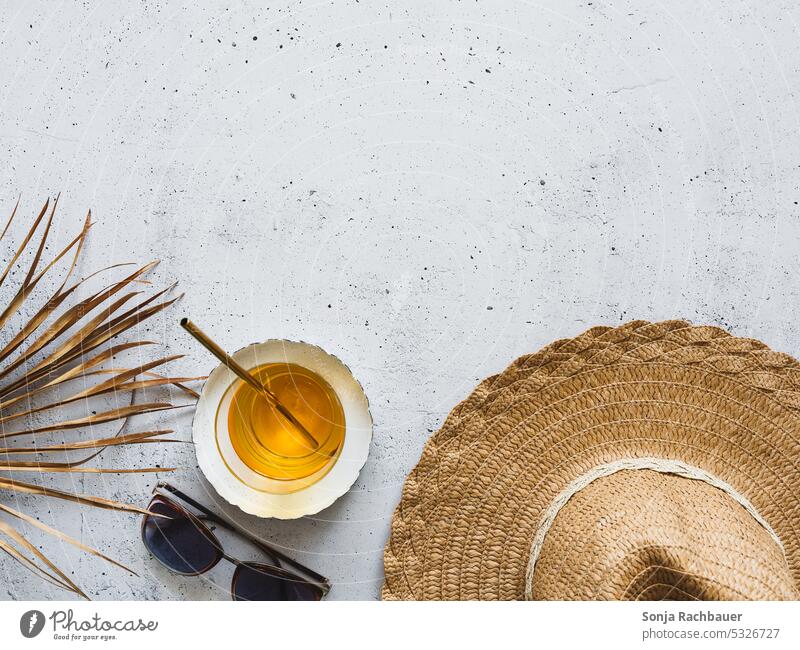 Ein Sonnenhut, ein Cocktail und ein Palmblatt auf einem grauen Tisch. Flat lay. Sommer Sonnenbrille Ferien & Urlaub & Reisen Sommerurlaub Studioaufnahme Design