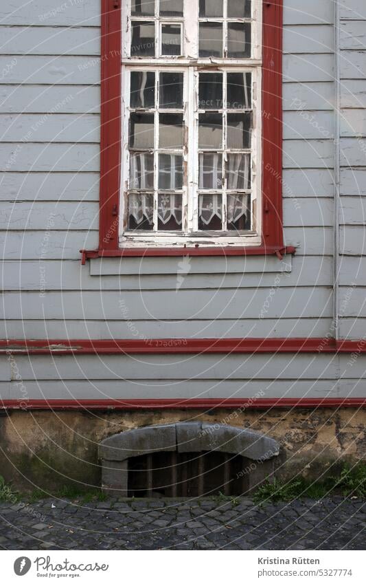 sprossenfenster mit gardine spitzengardine holzverkleidung fassade anstrich kellerfenster unkraut haus gebäude pflastersteine architektur altbau patina monschau