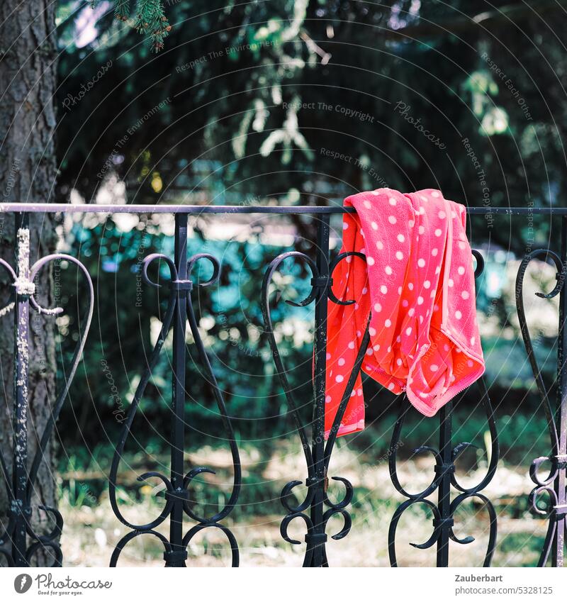 Eine rote Jacke mit weißen Punkten liegt über einem schmiedeeisernen Zaun geschmiedet hängen verloren vergessen gefunden Fundbüro Kind Kindheit beänstigend
