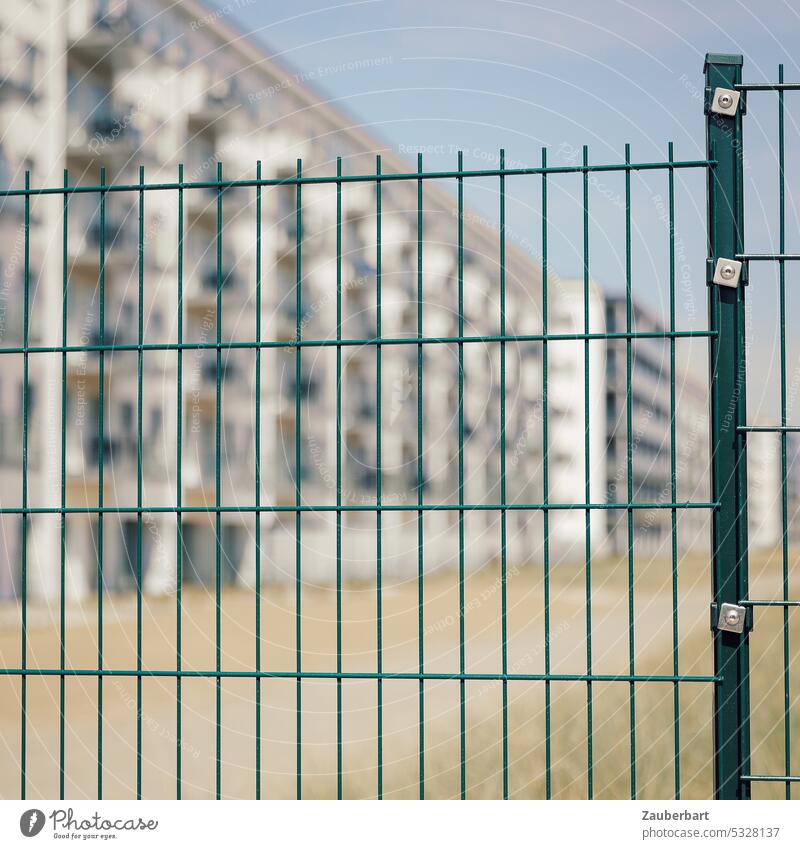 Moderne Wohnanlage mit Ferienwohnungen hinter einem neuen Gitterzaun Wohnhaus Hochhaus Zaun rechteckig Sperre abgesperrt trist trostlos sonnig Gebäude