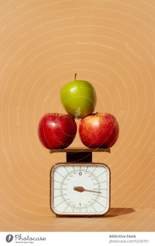 Reife Äpfel auf einer Waage vor farbigem Hintergrund Apfel wiegen Skala Frucht Diät Vitamin Gesundheit Lebensmittel Konzept frisch reif rot grün organisch