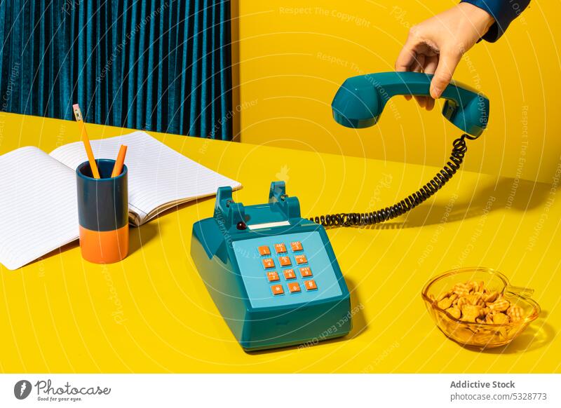Person, die das Telefon auflegt, in der Nähe von Büromaterial aufhängen Mobilteil retro ruhend Notebook Planer Keks Vorrat altmodisch altehrwürdig kreativ