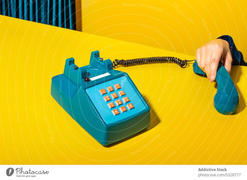 Person, die das Telefon auf gelbem Hintergrund abnimmt abholen aufhängen Mobilteil retro ruhend Vorrat altmodisch altehrwürdig kreativ Schaltfläche Draht Gerät